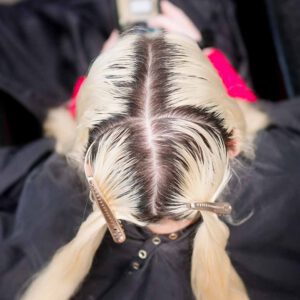 A stylist applying bleach to hair roots